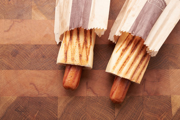 Two hot dogs lying on the wooden table