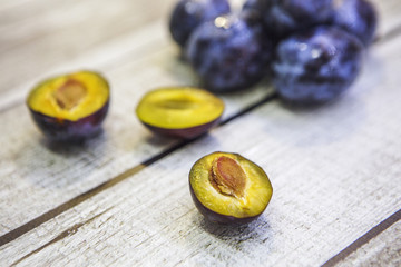 Слива на деревянном столе. Половинки сливы с косточками и без.