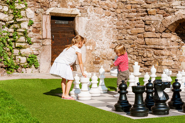Two little kids playing giant chess outdoors