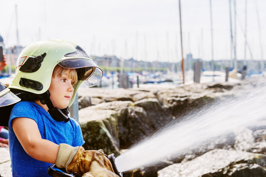 Little boy pretending to be firefighter, open doors day at fire station. Future profession for children. Educational programme for schoolkids