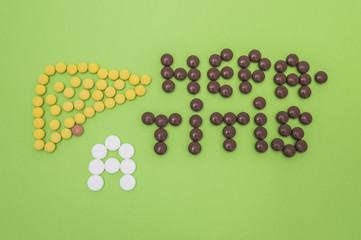 Figure or shape of human liver and the diagnosis of hepatitis A sign made of yellow, brown and white pills or tablets on a green paper background 