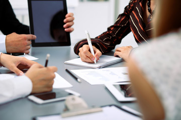 Group of business people at meeting, close up. Boss pointing into tablet computer monitor