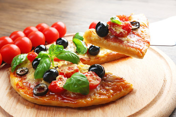 Sliced tasty pizza and fresh cherry tomatoes on wooden plate