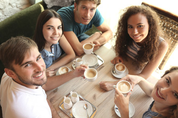 Happy friends drinking coffee in cafe