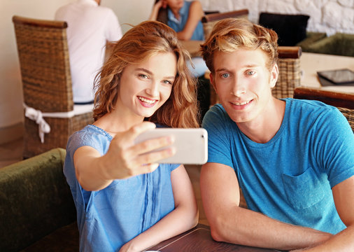 Happy couple taking selfie in cafe