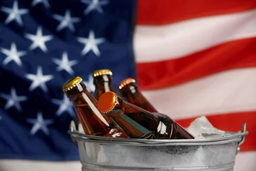 Fototapeten Bucket with cold beer bottles on American national flag background © Africa Studio