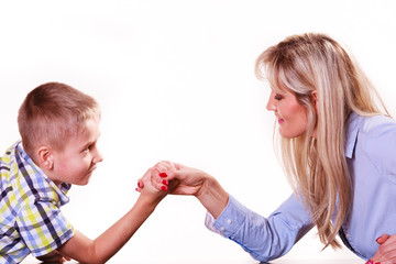 Mother and son arm wrestle sit at table.