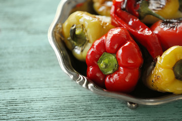 Plate with roasted peppers on wooden background