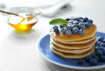Tasty pancakes with blueberries and mint on table