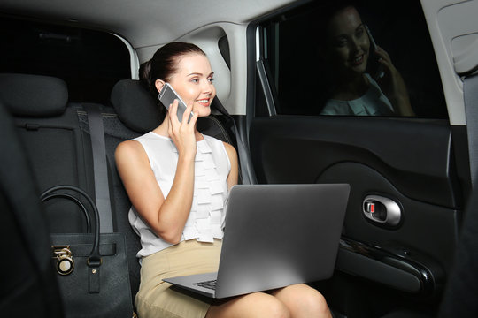 Beautiful business woman sitting in back seat of car