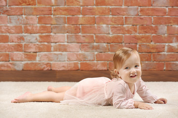 Fototapeta premium Little fashion-girl in pink dress posing on a brick wall background