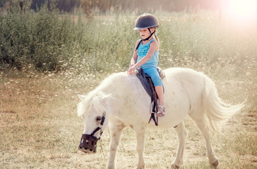 Little girl on the horse. White poni.