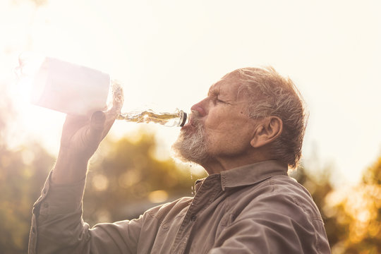 Пенсионер пьет воду на проироде