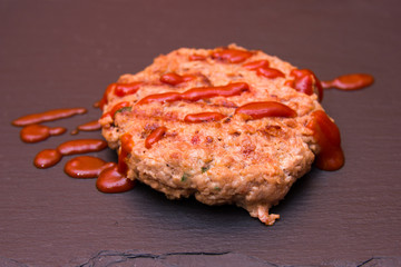 Meatball with ketchup on a slate floor