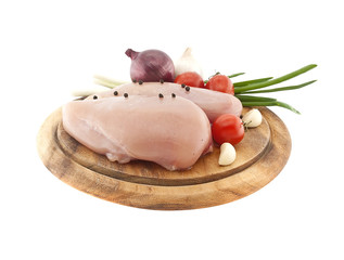 Raw chicken breasts on wooden cutting board with vegetable