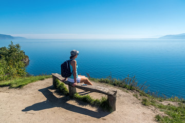 Girl sitting on a bench oand admire lake baikal