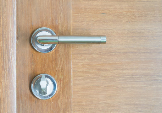 Silver metal door handle and brown wood door