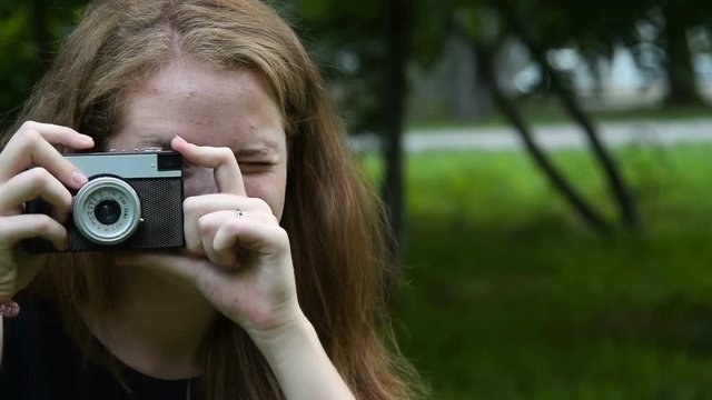 Smiling teenager girl taking picture with retro camera outdoor