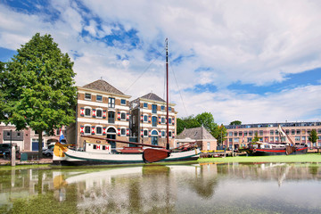 Ancient renovated mansion with a white moored boat mirrored in a canal. .