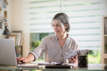 a woman of 50 years who works at home with techologiques devices