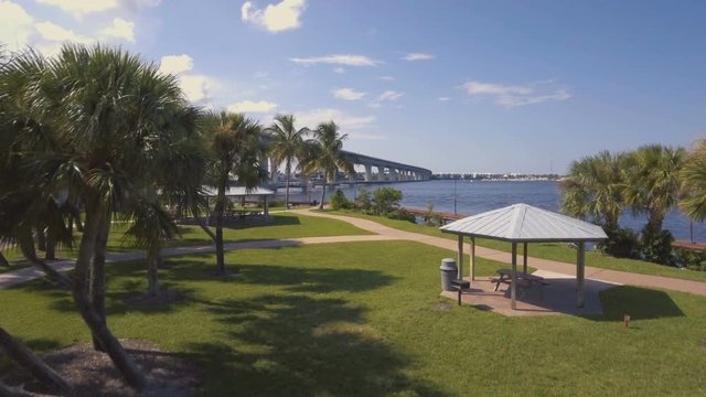 Aerial flying from a city park to a bridge with highway traffic over St Lucie River in Florida.