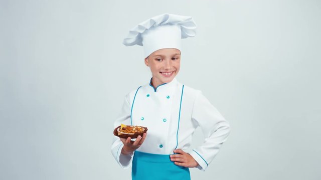 Baker enters the frame with little cake with nuts and gives you it. Chef 7-8 years smiling at camera. Isolated on white