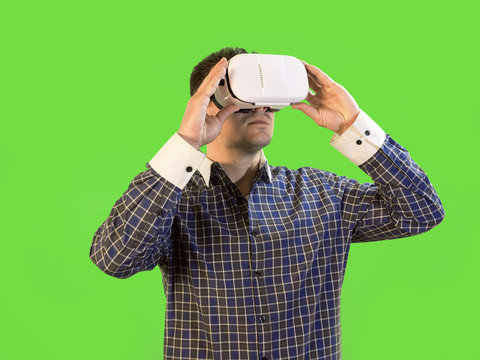 Man by Green Screen Holds Virtual Reality Headset to His Eyes