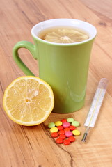 Pills, thermometer and hot tea with lemon for colds, treatment of flu and runny