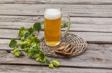 Glass of beer and brown bread with sprats on a wooden table