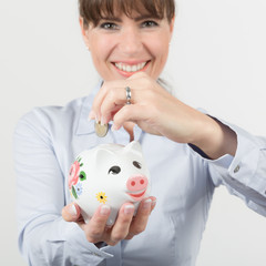 Fototapeta na wymiar Frau wirft Geldstück in Sparschwein