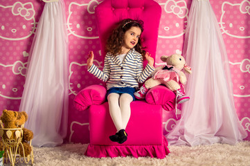 Fototapeta premium beautiful little curly girl in a big soft chair