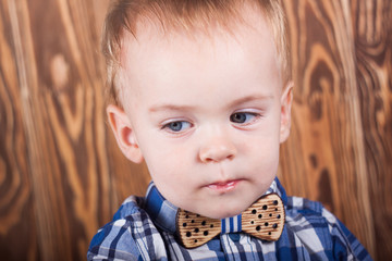 Small child in a plaid shirt with a bow tie.