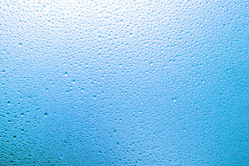 Water droplets on the glass with a colored background. Drops of