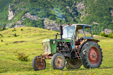 Old rusted tractor parked in nature.