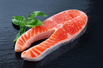 Fresh salmon with basil on a dark background