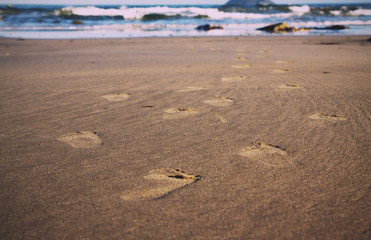 Footprints in the sand on Polzeath beach Vintage Retro Filter.