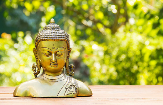 Buddha statue on natural blur green background. Spa concept. Calmness and tranquility. Copy space. Statuette of brass. 
