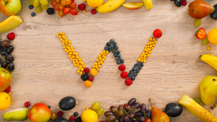 Fruits made letter W. The letters are made up of fruits. Alphabet on a table. W