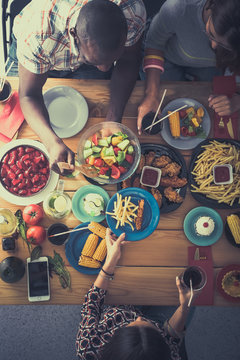 Top view of group of people having dinner together while sitting at wooden table