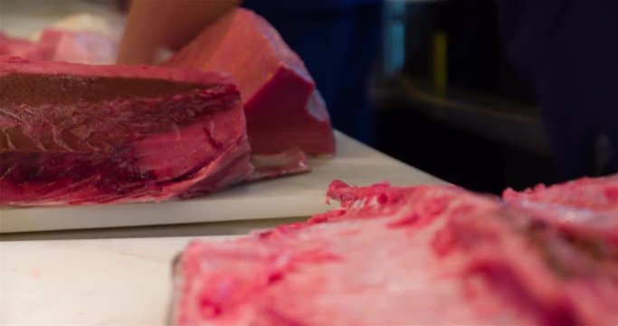 Chef hands cutting with knife raw bluefin tuna 4k close up bokeh video in sushi restaurant kitchen. Asian japanese cuisine.