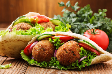 Falafel and fresh vegetables in pita bread on wooden table