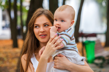 Two happy people loving mother and her baby son autumn outdoors in park.