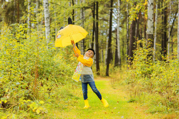 Girl with yellow umbrella walking in the forest autumn day