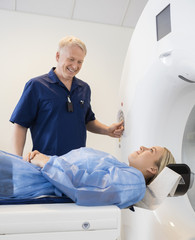 Professional Looking At Female Patient Undergoing CT Scan