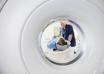 Male Doctor Looking At Patient Undergoing CT Scan