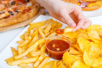 Pretty young woman working at the computer and eating fast food. Unhealthy Lifestyle