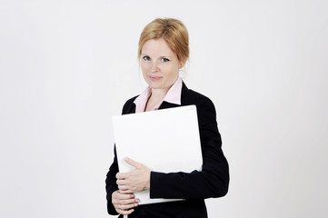 Naklejka premium Young freckled businesswoman is standing with a portfolio, looking into the camera with an elegance smile. Studio shot with light background. Isolated.