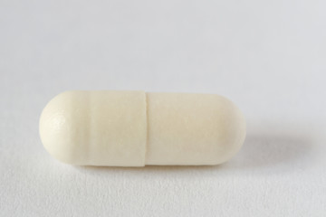 White pill capsule on light background. Macro