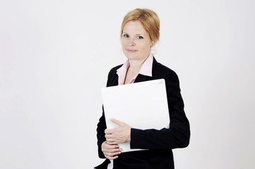 Naklejka premium Young freckled businesswoman is standing with a portfolio, looking into the camera with an elegance smile. Studio shot with light background. Isolated.