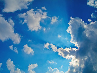 blue cloudy sky with beautiful sunbeams seen from below